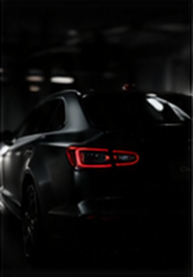 Black car with tail lights glowing in a dark garage